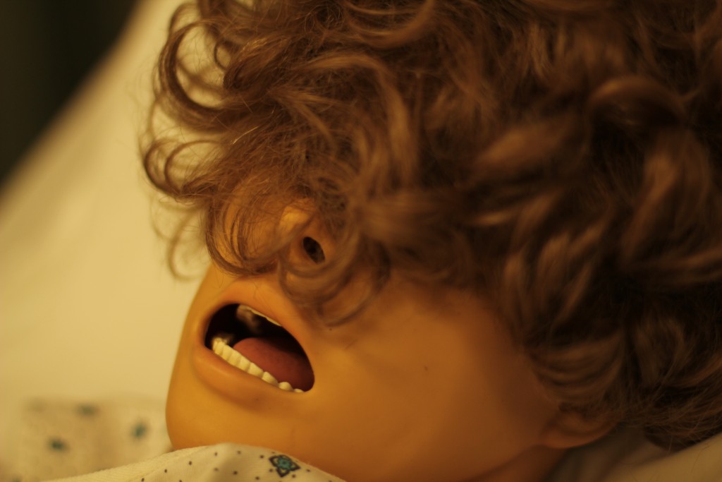 A close-up portrait with curly brown hair, warm amber lighting, and deep shadows across the face, conveying a contemplative and slightly mysterious mood.